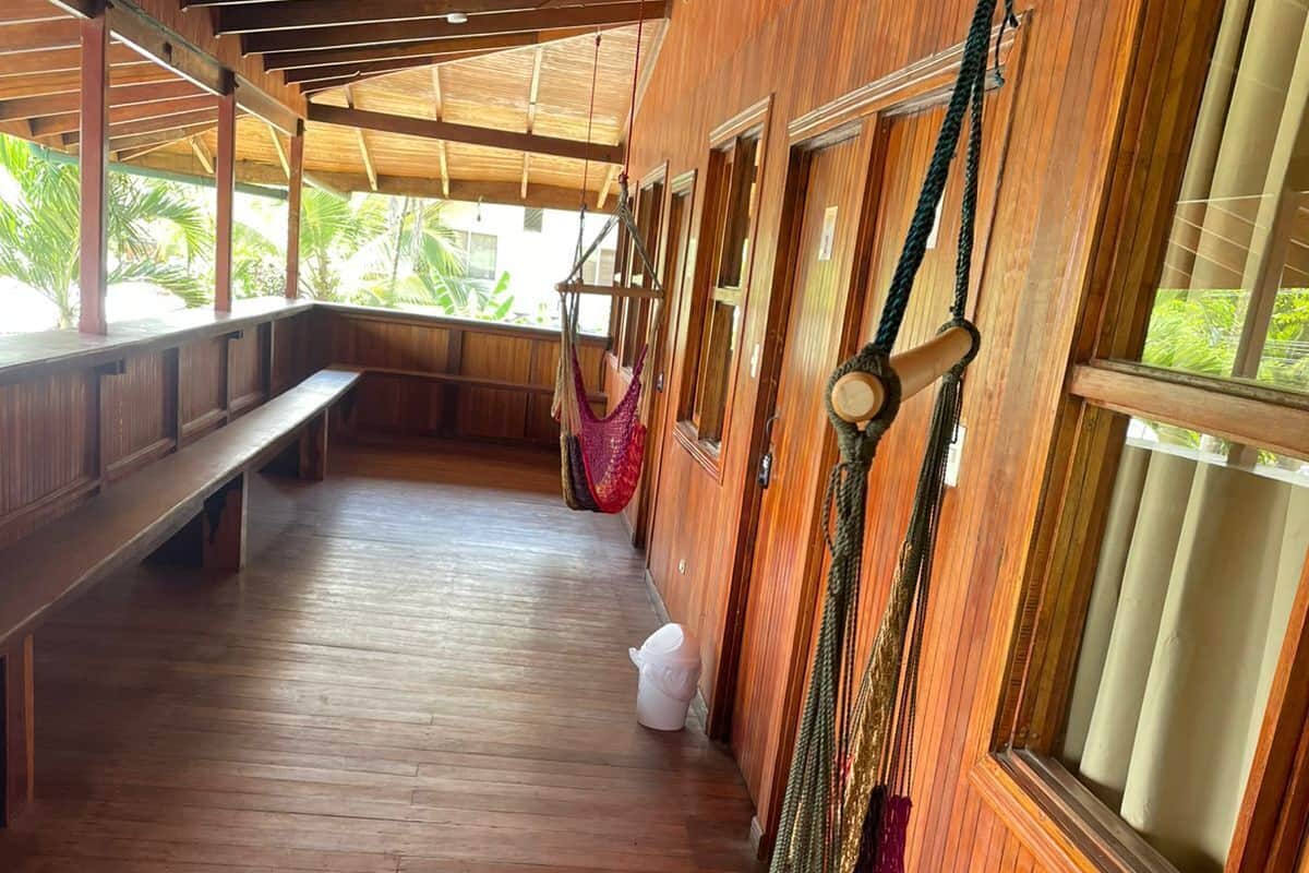 Un interior de madera con un banco, una hamaca y una ventana.
