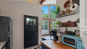 A modern kitchen with a black door, a coffee machine, a microwave, and a wooden countertop. - Hot Tub in the Poconos -Borders State Forest! (Tobyhanna)