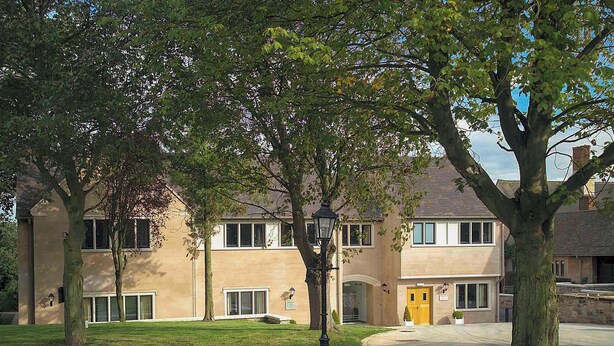 A two-story building with a beige facade, large windows, and a well-maintained lawn. - Knights Suite Rooms and Events (Royal Leamington Spa)