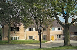A two-story building with a beige facade, large windows, and a well-maintained lawn.