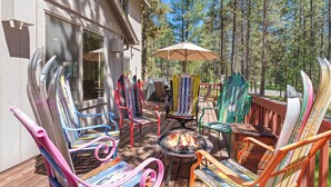 Eine Terrasse mit bunten Adirondack-Stühlen, einer Feuerstelle und einem überdachten Tisch.
