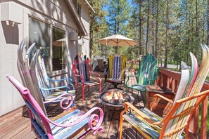 Une terrasse agrémentée de chaises Adirondack aux couleurs vives, d’un foyer et d’une table couverte.