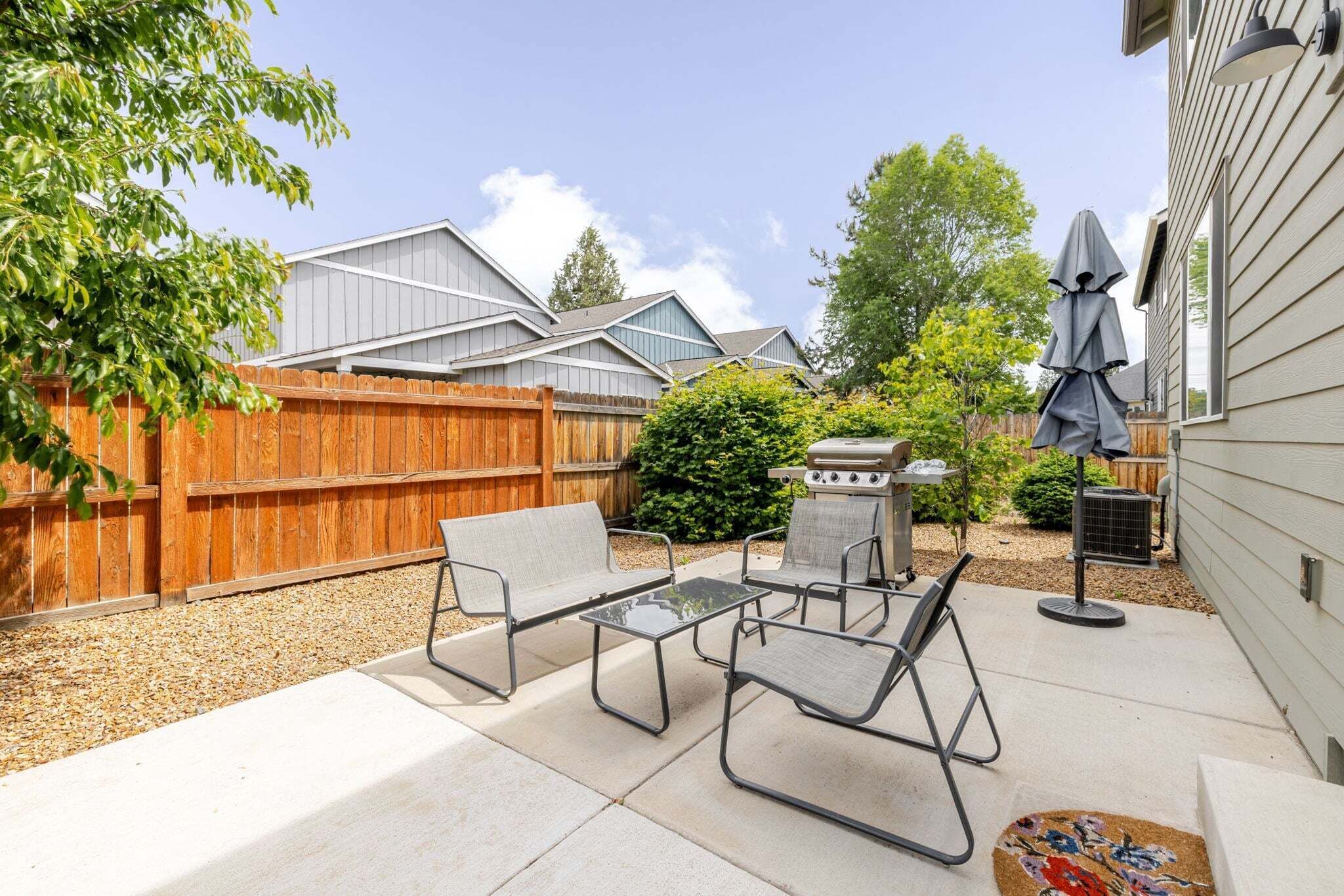 A patio with outdoor furniture, a grill, and a wooden fence.