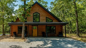 Eine Blockhütte mit Satteldach, großen Fenstern und einer Veranda.
