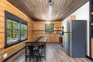 Eine moderne Küche mit Holzwänden, einem großen Kühlschrank und einem Esstisch mit Stühlen.
