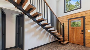 A staircase with wooden steps and black metal railings, a wooden door with a window, and a view of trees through the window. - Modern Log Cabin - Boat Ramp & Rock Crawl nearby (Eucha)