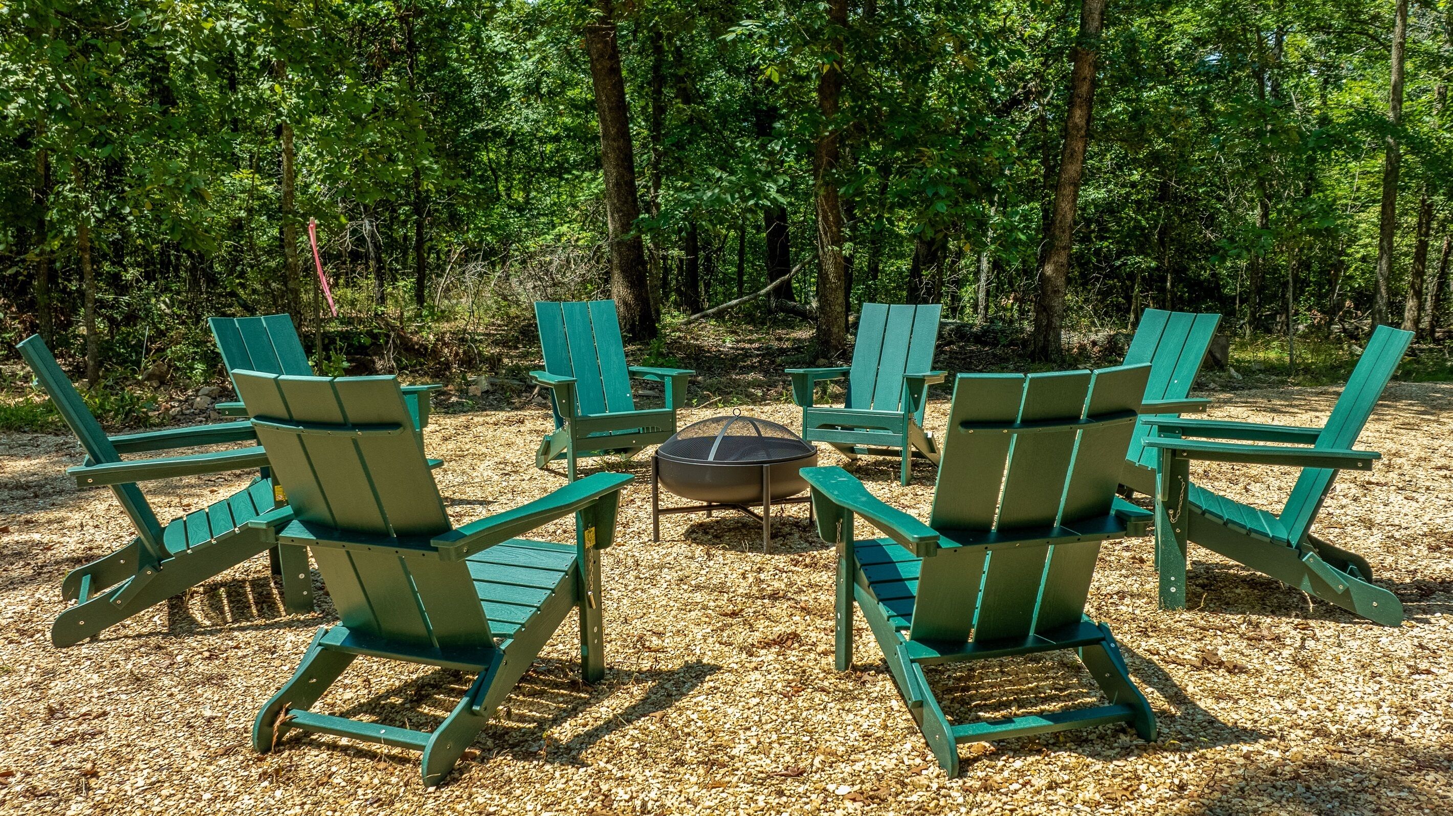 Outdoor seating with a fire pit in a forested area.