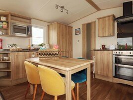 Una cocina con gabinetes de madera, un microondas, una estufa y dos sillas amarillas.