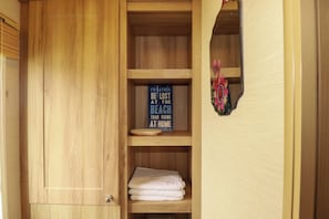 Ein Holzkabinent mit einem blauen Schild, einem gefalteten weißen Handtuch und einem Spiegel mit floralem Dekor.