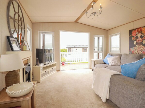 A living room with a television, sofa, and a decorative bowl on a table. - Morwenna (Padstow)