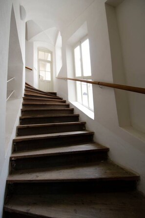 Eine Treppe mit Holzdielen und weißen Wänden, die zu einer Tür oben führt.