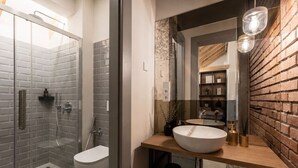 Un bagno moderno con cabina doccia in vetro, un water bianco e un mobile lavabo in legno con un lavandino grande.