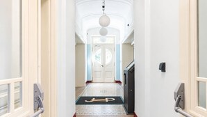 Een hotelgang met tapijt, een deur en een intercom bevestigd aan de muur.