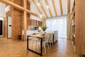 Eine moderne Küche mit Backsteinwand, Holzbalken und einem Essbereich mit Tisch und Stühlen.