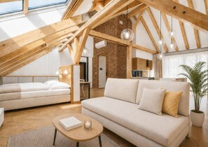 Ein moderner Lofts-Wohnraum mit freiliegenden Holzbalken, einer Ziegelwand und einem großen Fenster.