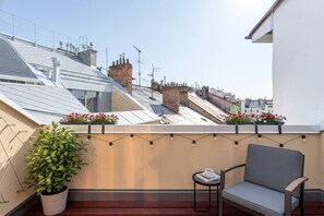 A rooftop terrace with a chair, potted plant, and flower boxes. - Cozy Attic Loft with Terrace in Prime Location (Prague 2)