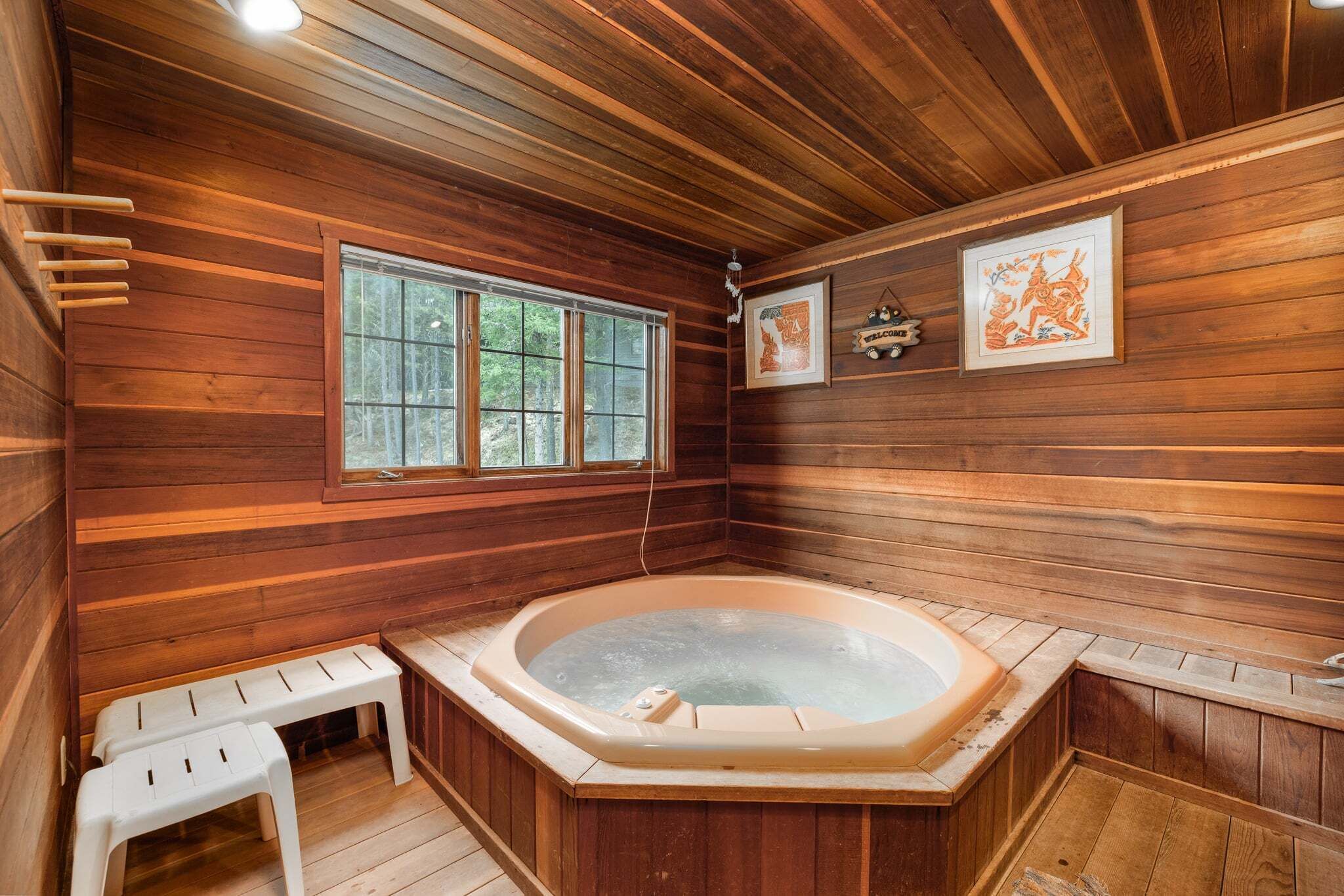 A wooden cabin with a hot tub, wooden benches, and framed artwork on the walls.