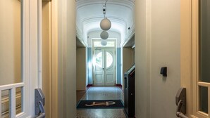 A hallway with a carpet, a door at the end, and a light fixture above. - Stylish Residence in Parkside Vinohrady (Prague 2)