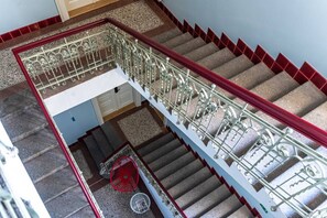 Eine mehrstufige Treppe mit aufwendiger Metallgeländerung und roten Akzenten.