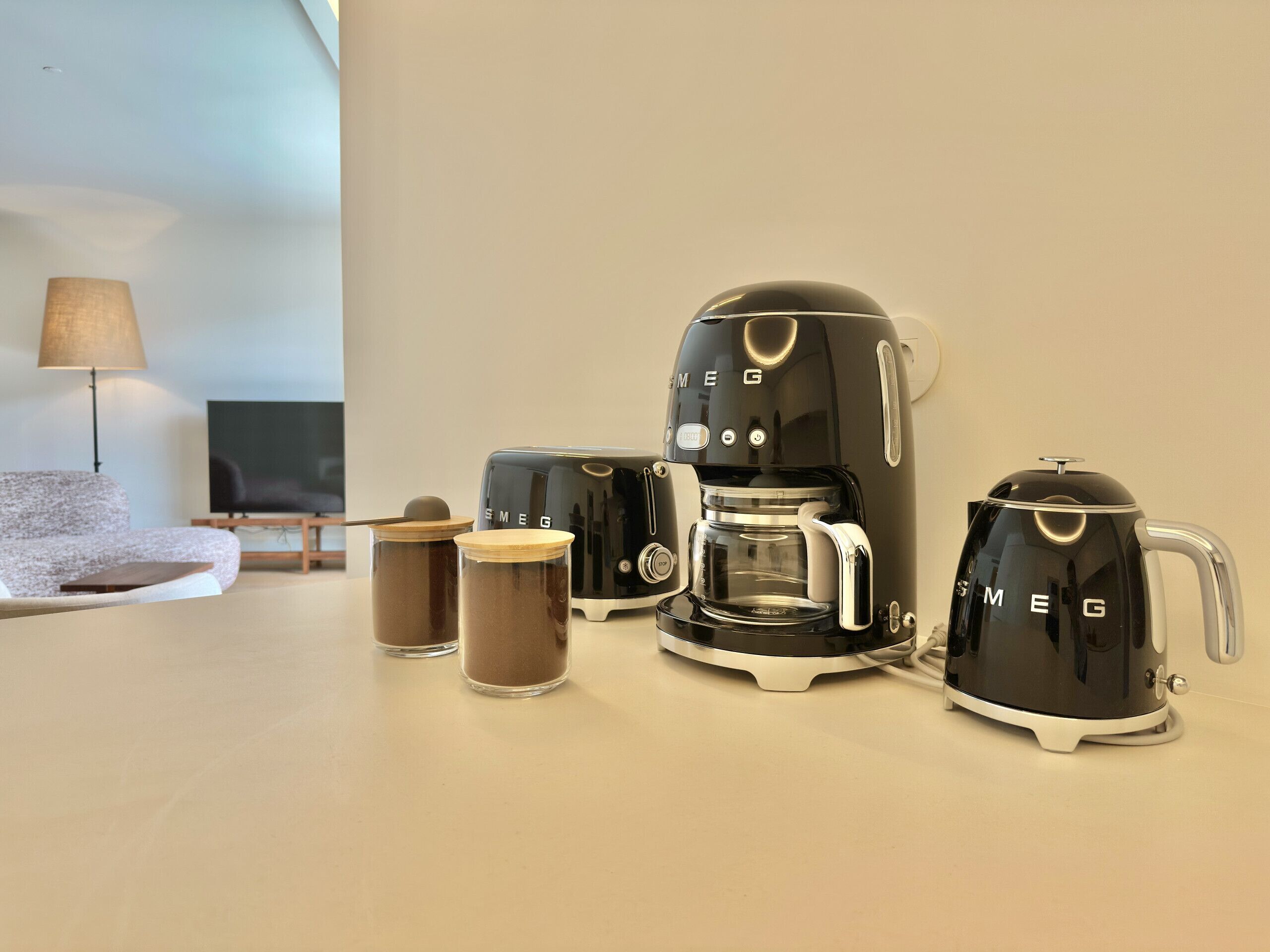 Un salon moderne avec un canapé, une machine à café, deux tasses à café et un téléviseur.