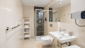 Une salle de bain moderne avec une douche à parois de verre, des toilettes blanches, un lavabo avec un miroir et un porte-serviettes.