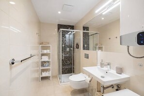 Ein modernes Badezimmer mit Duschkabine aus Glas, Toilette in Weiß, Waschbecken mit Spiegel und Handtuchhalter.