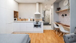 Une cuisine moderne avec des meubles blancs, un îlot central et un coin repas comprenant une table et des chaises.