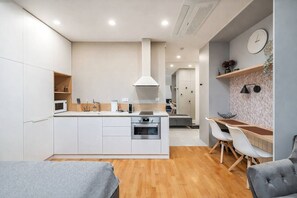 Eine moderne Küche mit weißen Schränken, einer zentralen Kochinsel und einem Essbereich mit Tisch und Stühlen.