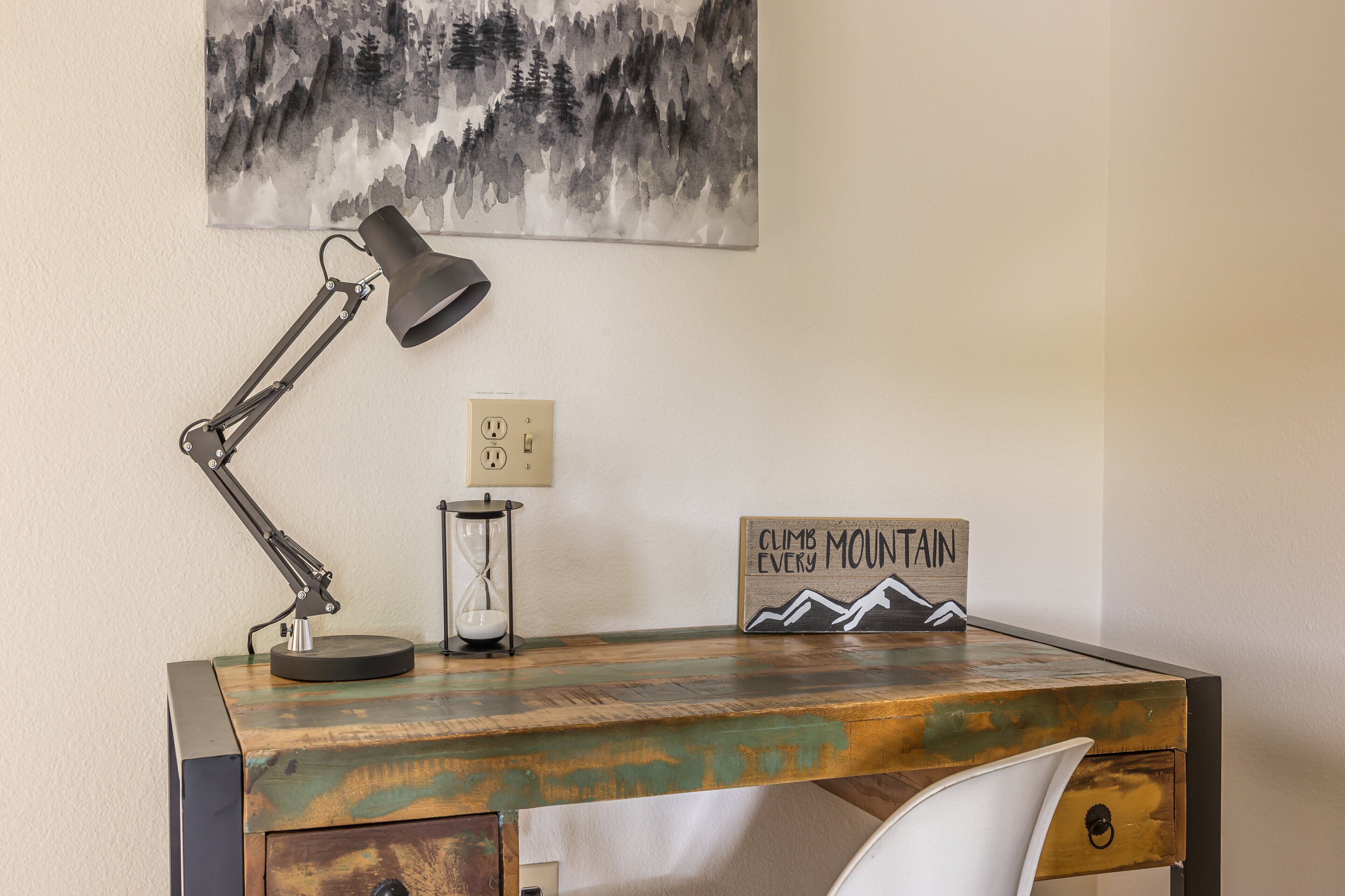 Un bureau avec une lampe, un sablier et une affiche motivante.