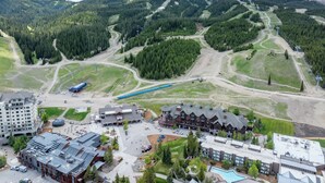 A mountain resort with a ski lift, buildings, and a pool area.
