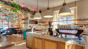 A modern kitchen with a central island, pendant lighting, and a colorful mural on the wall. - Riverside Urban Oasis in Prague’s Coolest District (Prague 8)