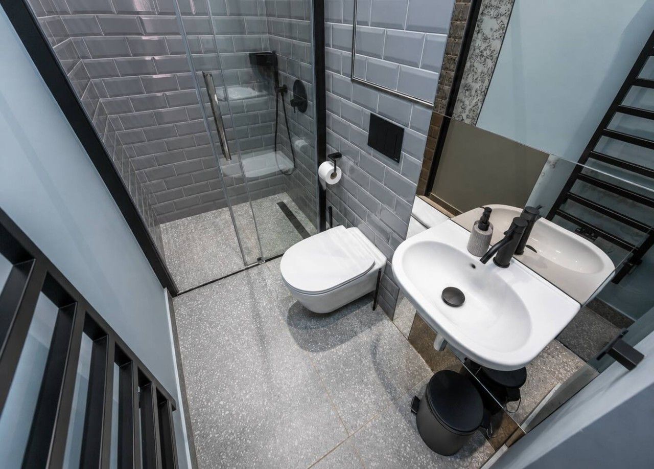 Een badkamer met een douche met glazen wand, een toilet en een wastafel met spiegel erboven.