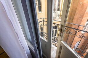 Blick durch eine Tür mit einem Metall-Balkonläufer, einem Holztürrahmen und einem Fenster mit Metallgitter.