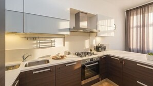 A modern kitchen with dark wood cabinets, stainless steel appliances, and a white countertop. - Comfortable Two-Bedroom Residence in the Heart of Prague (Prague 1)