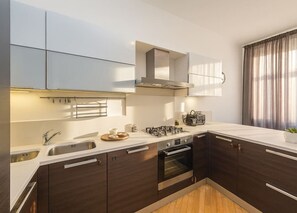 Eine moderne Küche mit dunklen Holzschränken, Edelstahlgeräten und einer weißen Arbeitsplatte.