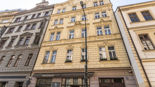 A multi-story building with a restaurant on the ground floor, ornate architectural details, and a street lamp. - Comfortable Two-Bedroom Residence in the Heart of Prague (Prague 1)