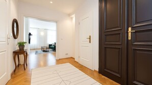 A hallway with a dark wooden door, a white rug, and a small table with a plant. - Comfortable Two-Bedroom Residence in the Heart of Prague (Prague 1)