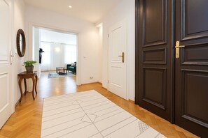 Ein Flur mit einer dunkelholzigen Tür, einem weißen Teppich und einem kleinen Tisch mit einer Pflanze.