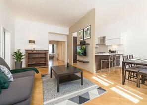 Ein modernes Wohnzimmer mit Sofa, Couchtisch und Essbereich mit Stühlen.