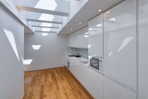 Eine moderne Küche mit weißen Schränken, Holzboden und Oberlichtern für natürliches Licht.