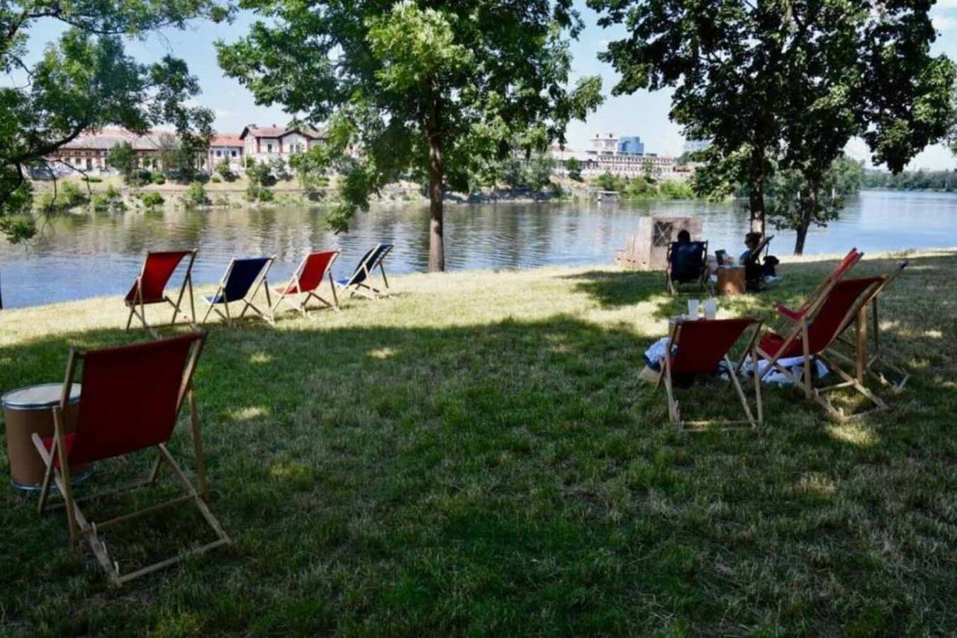 A lakeside setting with lawn chairs and a dining table, suggesting a dining area.