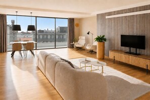 Un saló modern amb un sofà, una taula de centre, una televisió i una zona de menjador amb cadires i una taula.