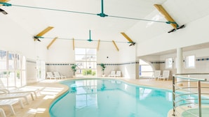 An indoor swimming pool with clear glass walls, white tiled floors, and multiple lounge chairs. - Grand Loire Valley Family Maisonette (Azay-le-Rideau)