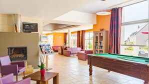 A billiards table, a fireplace, and a pool table in a room with orange walls and large windows. - Grand Loire Valley Family Maisonette (Azay-le-Rideau)