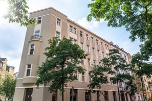 A multi-story building with a flat facade, large windows, and a corner balcony. - Elegant Attic Loft in Prime Vinohrady (Prague 2)