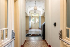A hotel hallway with a carpeted floor, a door at the end, and a light fixture above. - Cozy Attic Loft in Prime Location (Prague 2)