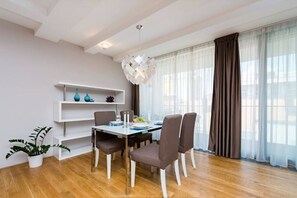 Ein Essbereich mit einem für vier Personen gedecktem Tisch, einer weißen Regaleinheit und einem Blumentopf.