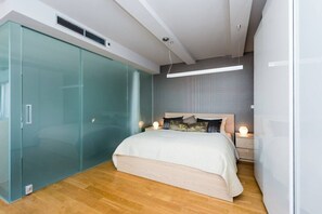 Ein modernes Schlafzimmer mit einem Bett, einem Glastisch und einem Nachttisch mit Lampe.