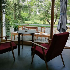 Ein Zimmer mit einem großen Fenster, einem runden Tisch und zwei roten Stühlen.