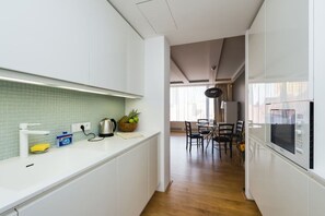 Eine moderne Küche mit weißen Schränken, einer grünen Spritzschutzwand und einem Essbereich mit Tisch und Stühlen.